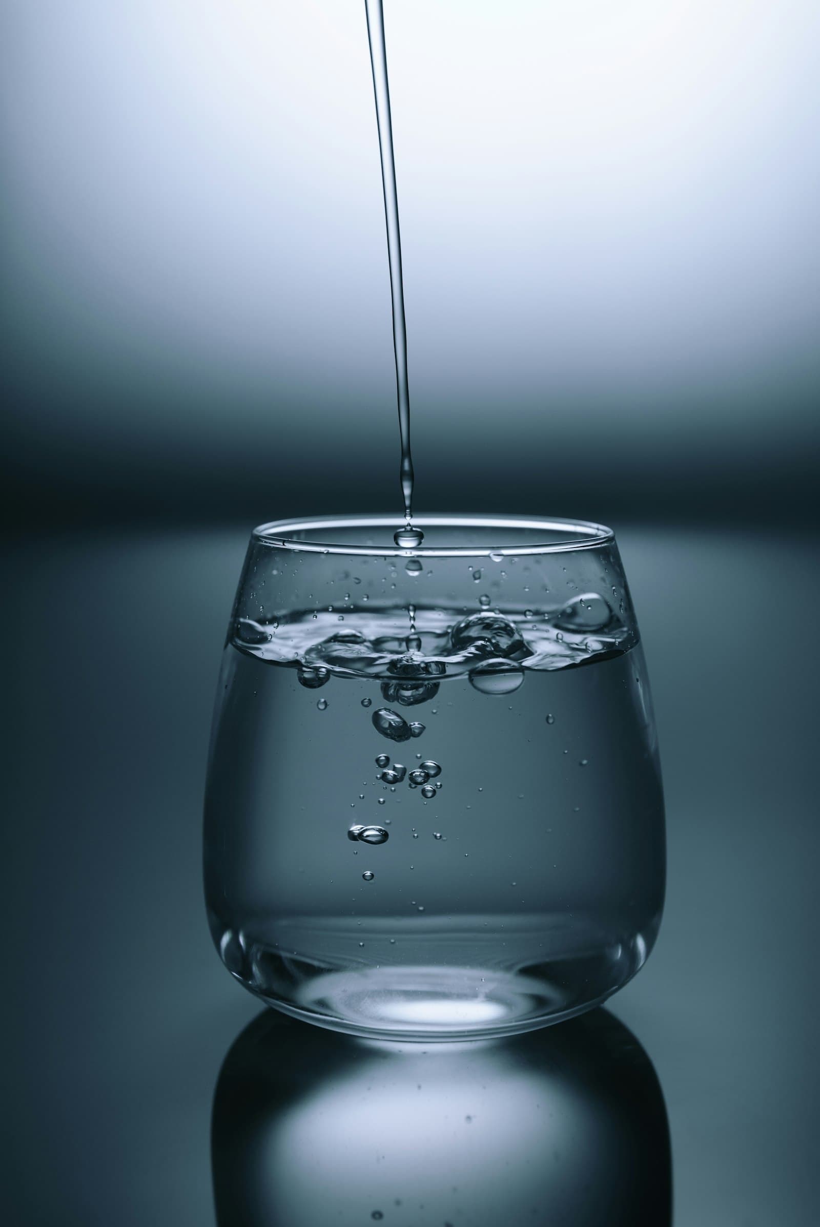 Clear water pouring from a chrome tap into a basin